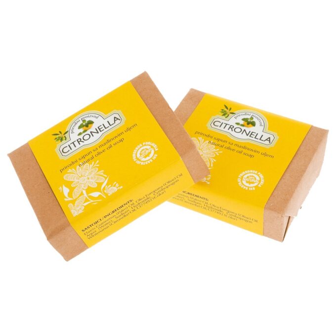 Ručno upakirani sapun. Papir kojim je upotrebljen za pakiranje sapuna je tamno bež boje te je na njemu još i žuti omot na kojem je amblem Herbae sa nazivom proizvoda (citronela sapun).