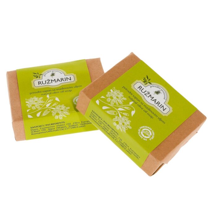 Ručno upakirani sapun. Papir kojim je upotrebljen za pakiranje sapuna je tamno bež boje te je na njemu još i zelenkasti omot na kojem je amblem Herbae sa nazivom proizvoda (sapun od ružmarina).
